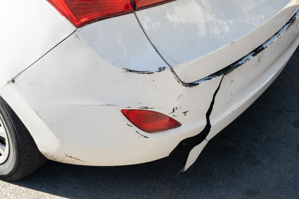 Close-up of cracked and scratched rear bumper showing damage that may require bumper repair or replacement.